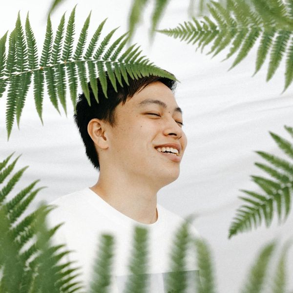 A person smiling peacefully with eyes closed, in a calm and well-lit environment.